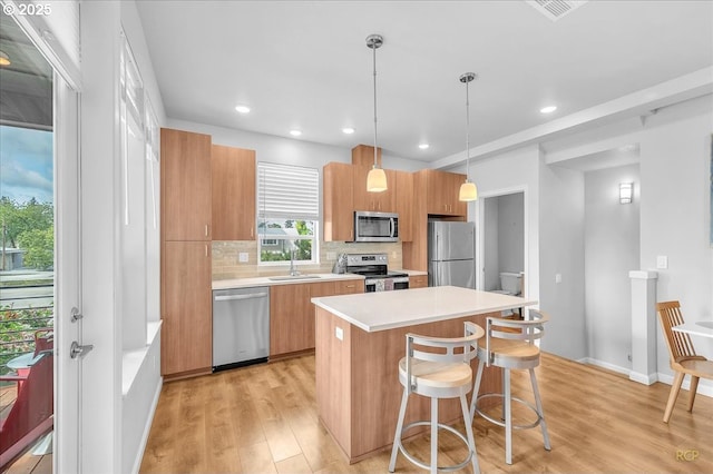 kitchen with a center island, a sink, decorative backsplash, light wood-style floors, and stainless steel appliances