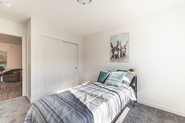 carpeted bedroom featuring baseboards and a closet