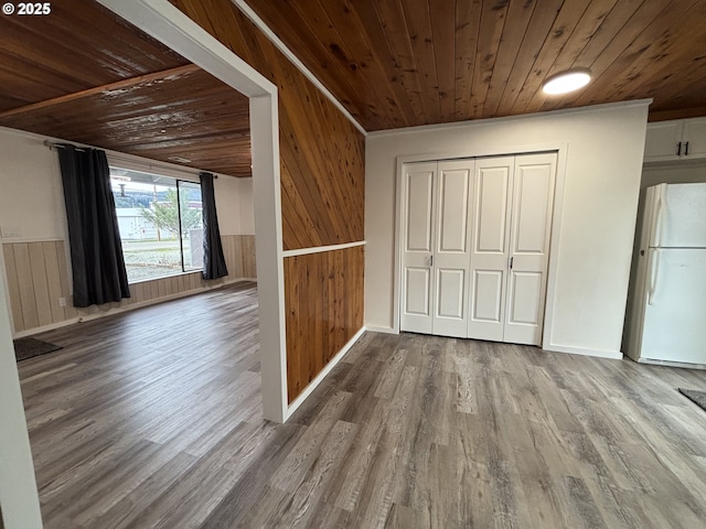 interior space with wooden ceiling, a wainscoted wall, wood finished floors, and freestanding refrigerator