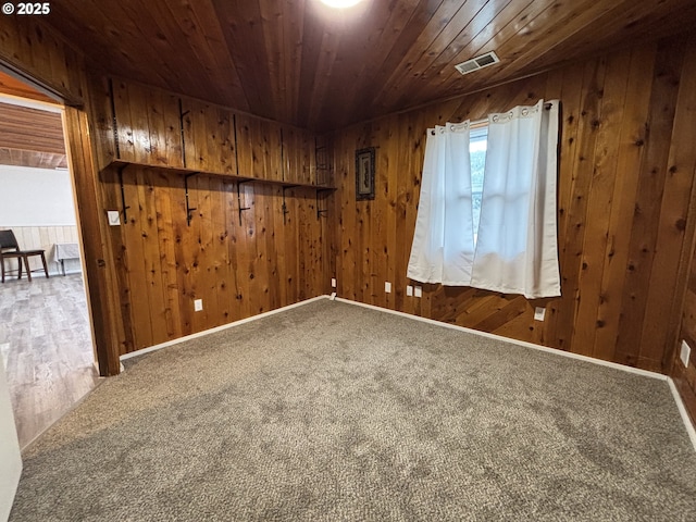 spare room with wooden ceiling, visible vents, wooden walls, and carpet flooring