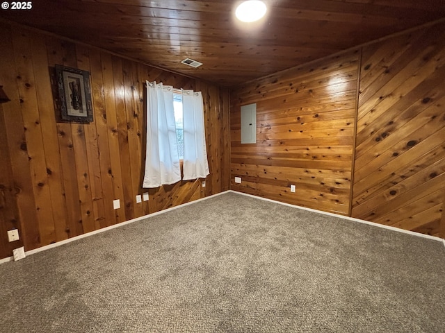 empty room featuring wooden walls, carpet floors, visible vents, baseboards, and wood ceiling