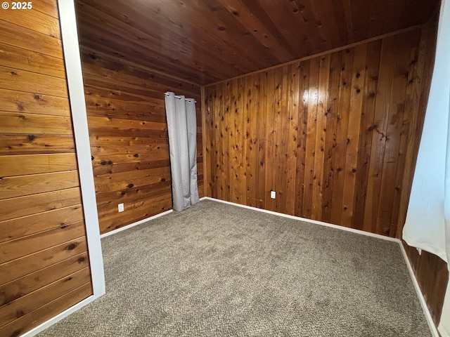 carpeted spare room with baseboards, wooden ceiling, and wooden walls