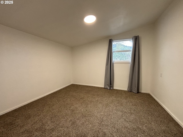 unfurnished room featuring dark colored carpet and baseboards