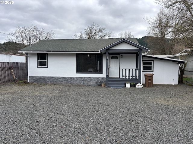 view of front of home featuring roof with shingles, fence, and stucco siding