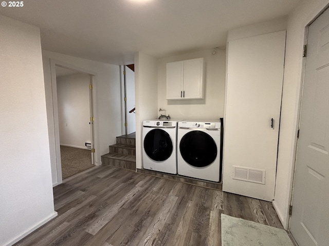 laundry room featuring visible vents, washing machine and clothes dryer, cabinet space, and dark wood-style floors