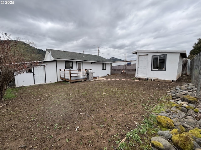 back of house with an outbuilding, fence, and a wooden deck