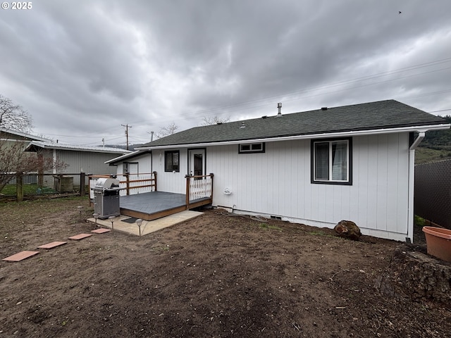 rear view of house featuring roof with shingles, fence, and a wooden deck