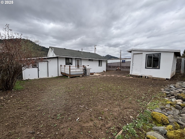 rear view of house with a wooden deck, fence, and an outdoor structure