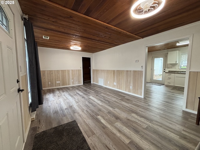 spare room featuring a wainscoted wall, dark wood-type flooring, wooden ceiling, and visible vents