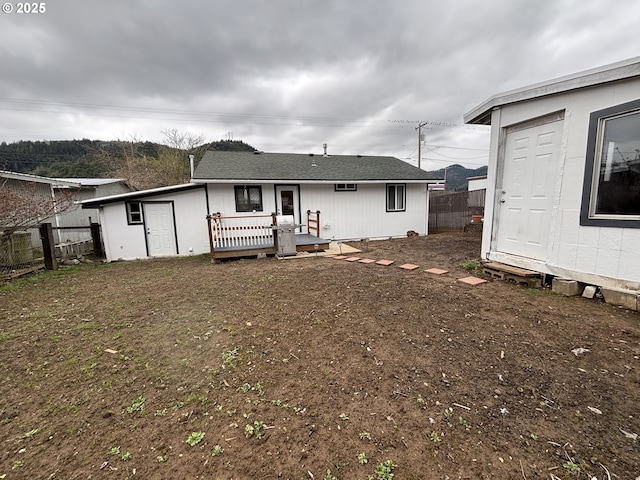 back of house featuring fence, a deck, and an outbuilding