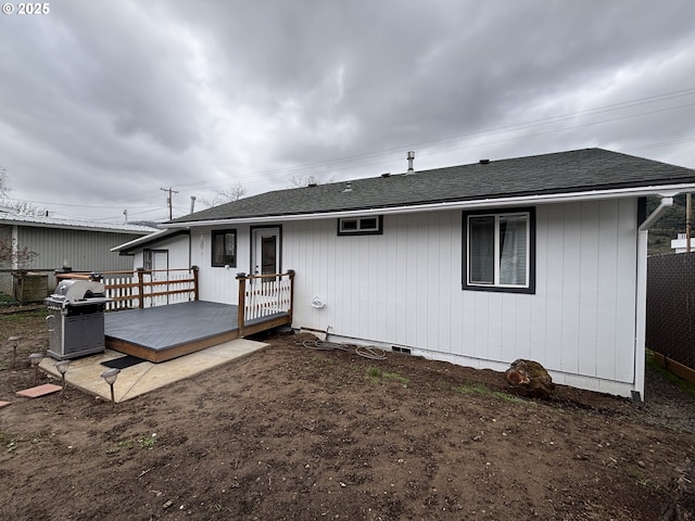 rear view of house featuring roof with shingles and a deck