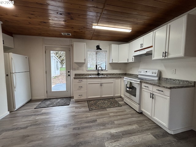 kitchen with under cabinet range hood, white appliances, a sink, white cabinets, and dark countertops