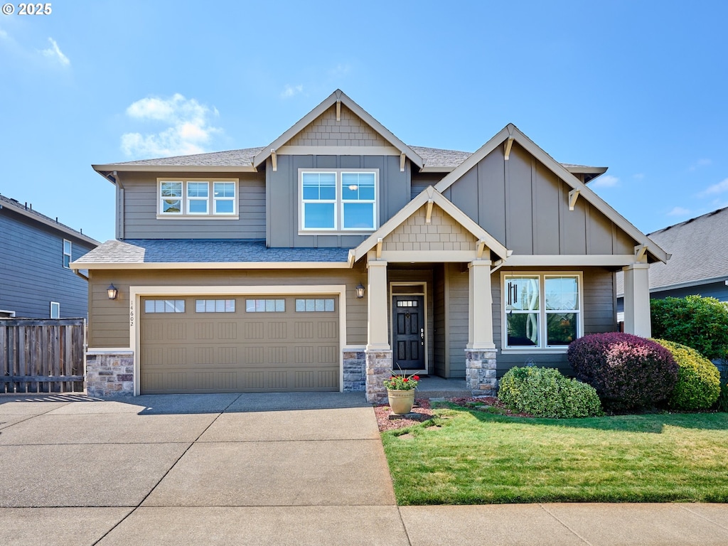 craftsman inspired home featuring a garage and a front lawn