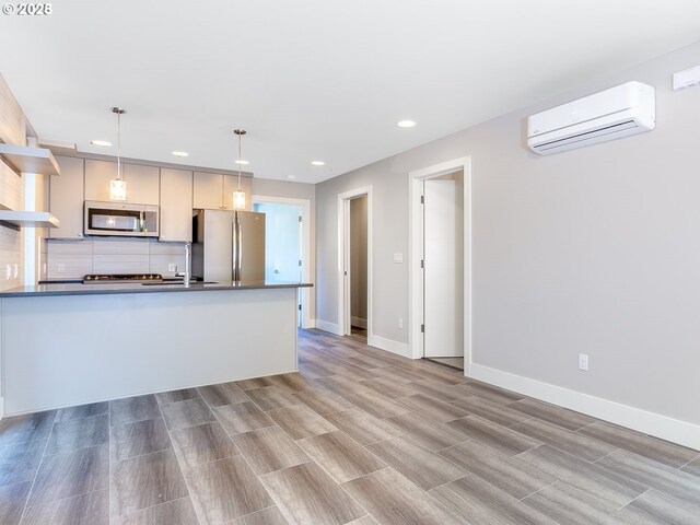 4984 NE 32nd Pl, Portland, OR 97211 - kitchen featuring stainless steel appliances, a wall unit AC, dark countertops, recessed lighting, and hanging light fixtures