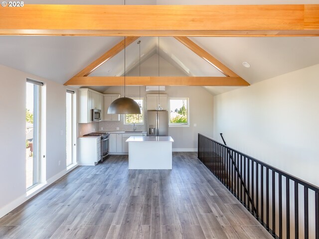 4984 NE 32nd Pl, Portland, OR 97211 - kitchen featuring appliances with stainless steel finishes, a kitchen island, white cabinetry, wood finished floors, and hanging light fixtures