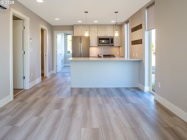 4984 NE 32nd Pl, Portland, OR 97211 - kitchen featuring appliances with stainless steel finishes, light countertops, recessed lighting, hanging light fixtures, and a peninsula