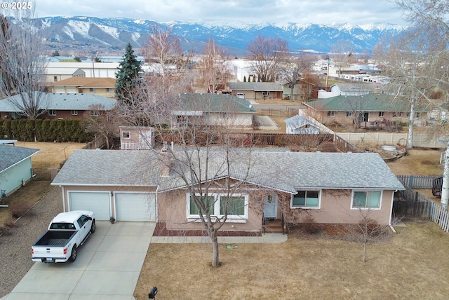 view of front of house featuring a mountain view, a garage, concrete driveway, and fence