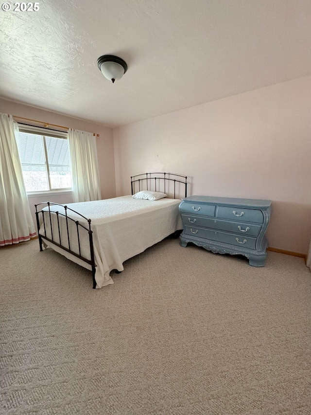 bedroom with light colored carpet, a textured ceiling, and baseboards