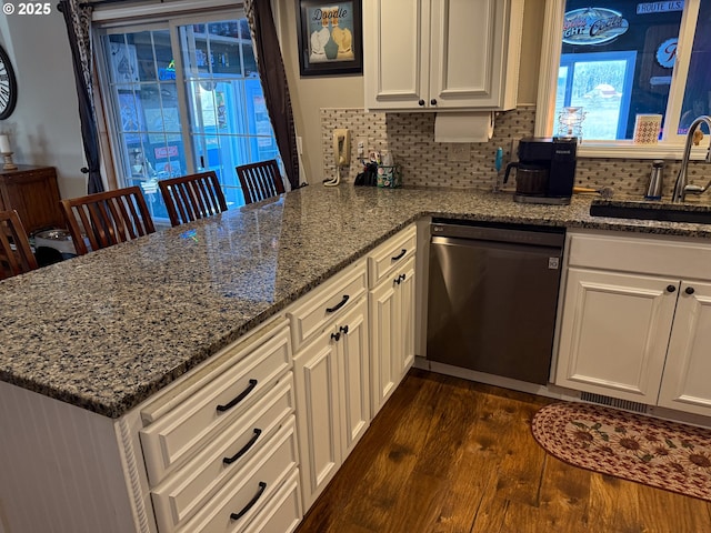 kitchen featuring sink, dishwasher, stone counters, backsplash, and dark hardwood / wood-style floors