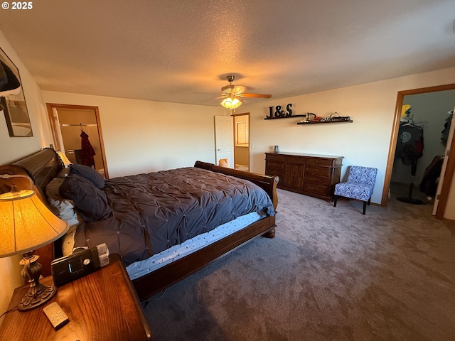 carpeted bedroom with ceiling fan, a spacious closet, a closet, and a textured ceiling