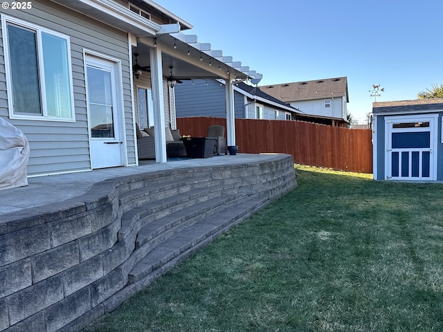 view of yard with ceiling fan, a storage unit, and a patio