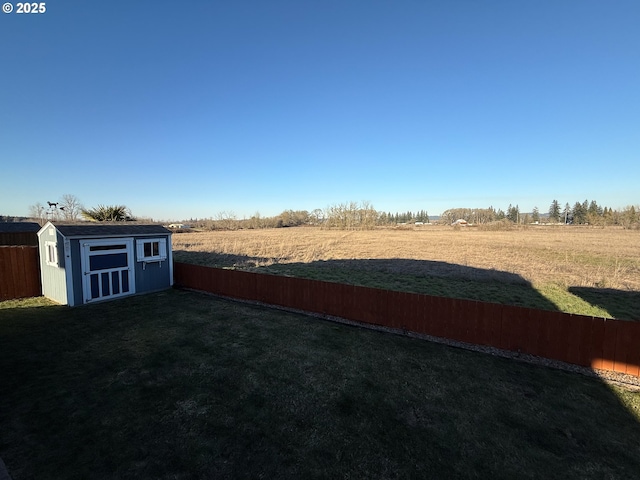 view of yard with a shed and a rural view