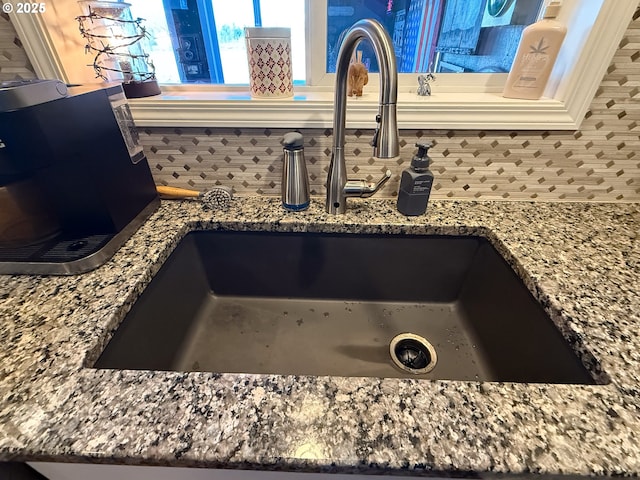 room details with stone counters, sink, and backsplash