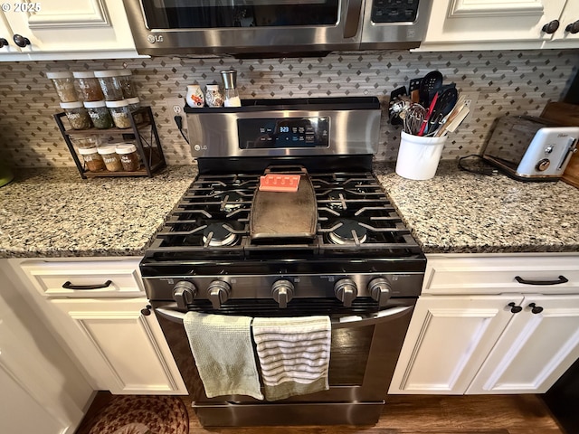 kitchen featuring stone counters, appliances with stainless steel finishes, dark hardwood / wood-style floors, white cabinets, and decorative backsplash