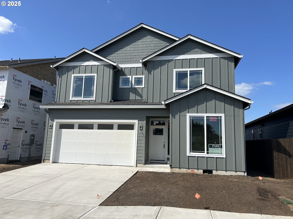 view of front facade featuring board and batten siding, an attached garage, fence, and concrete driveway