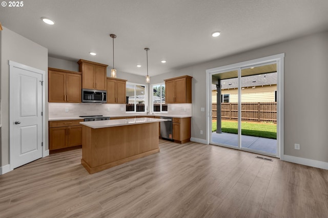 12216 NE 107th Way, Vancouver, WA 98682 - kitchen with stainless steel appliances, light wood-type flooring, backsplash, light countertops, and brown cabinetry