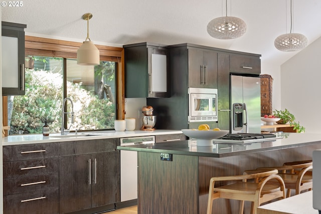 511 SW Colony Dr, Portland, OR 97219 - kitchen featuring stainless steel appliances, a breakfast bar, dark brown cabinetry, and hanging light fixtures