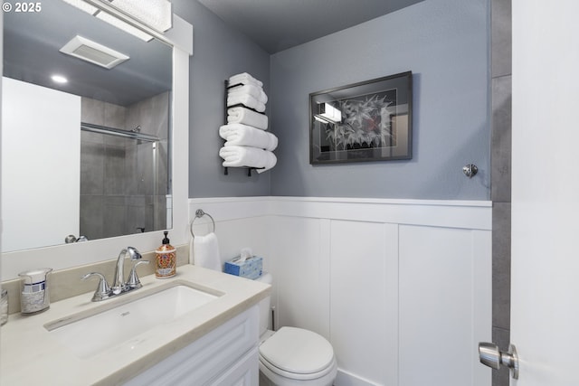 6234 SE 140th Ave, Portland, OR 97236 - full bathroom featuring a tile shower, toilet, vanity, a wainscoted wall, and a decorative wall