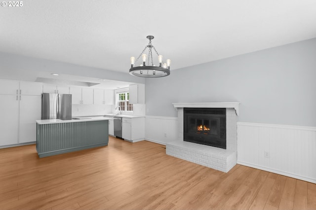 21689 SW Klickitat Ct, Tualatin, OR 97062 - unfurnished living room featuring a chandelier, a wainscoted wall, light wood-style flooring, and a fireplace
