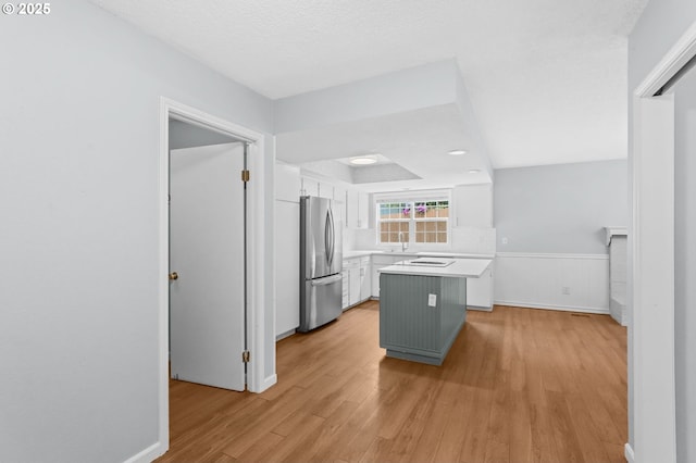 21689 SW Klickitat Ct, Tualatin, OR 97062 - kitchen with freestanding refrigerator, white cabinetry, light wood-style floors, light countertops, and a kitchen island