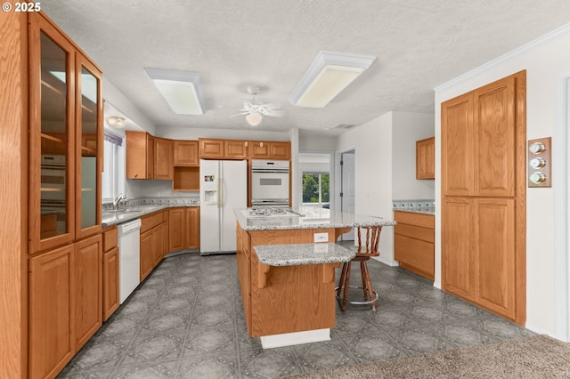 18183 SE Richey Rd, Gresham, OR 97080 - kitchen featuring white appliances, a kitchen island, a kitchen breakfast bar, ceiling fan, and light stone counters