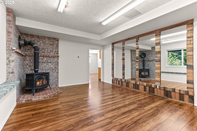 18183 SE Richey Rd, Gresham, OR 97080 - unfurnished living room featuring a wood stove, wood finished floors, and a textured ceiling