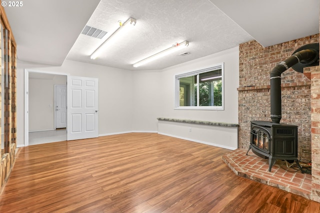 18183 SE Richey Rd, Gresham, OR 97080 - unfurnished living room with a wood stove, wood finished floors, and a textured ceiling