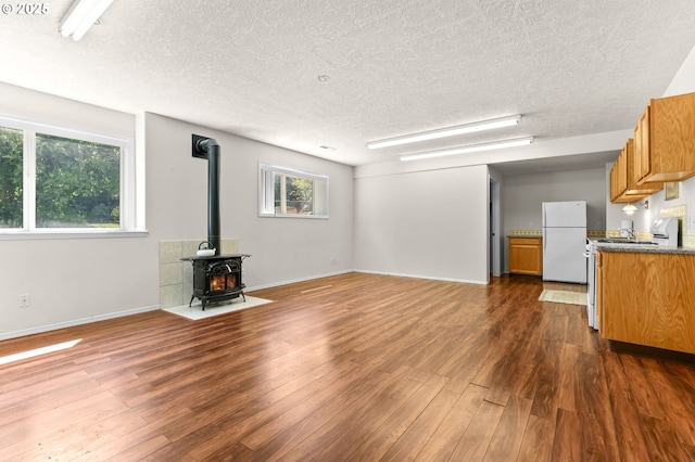 18183 SE Richey Rd, Gresham, OR 97080 - unfurnished living room featuring a textured ceiling, a wood stove, dark wood-style floors, and plenty of natural light