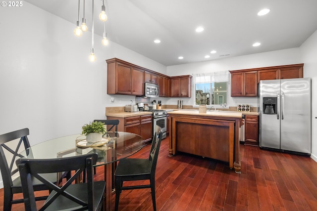 kitchen featuring a kitchen island, appliances with stainless steel finishes, dark wood-type flooring, and decorative light fixtures