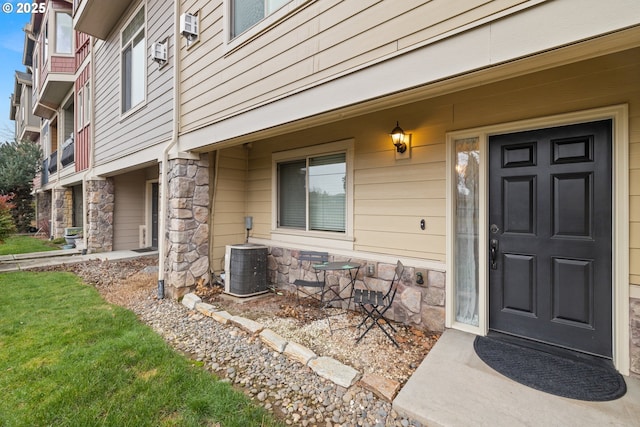 view of exterior entry featuring a yard and central air condition unit