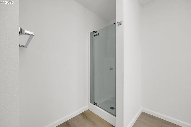 bathroom featuring a stall shower, wood finished floors, and baseboards