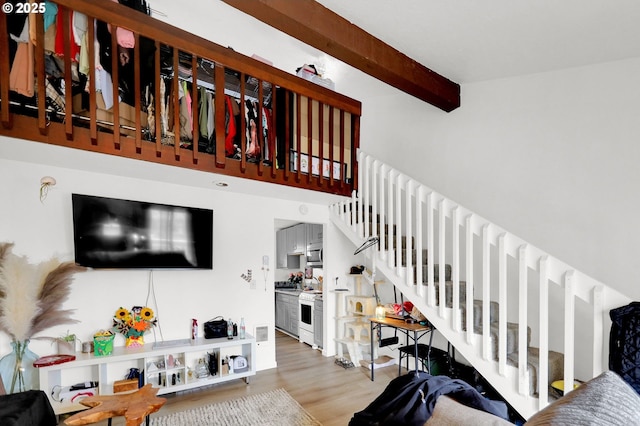 living room featuring beamed ceiling, stairway, and wood finished floors