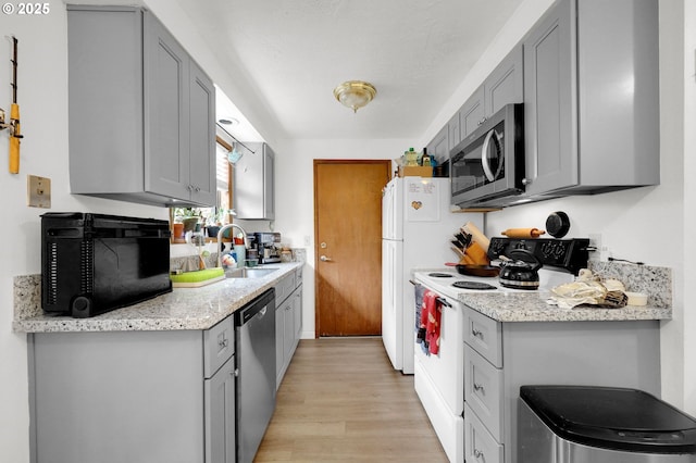 kitchen featuring appliances with stainless steel finishes, gray cabinets, and a sink