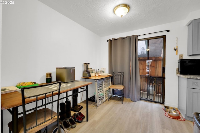 office space with light wood-type flooring, a textured ceiling, and baseboards