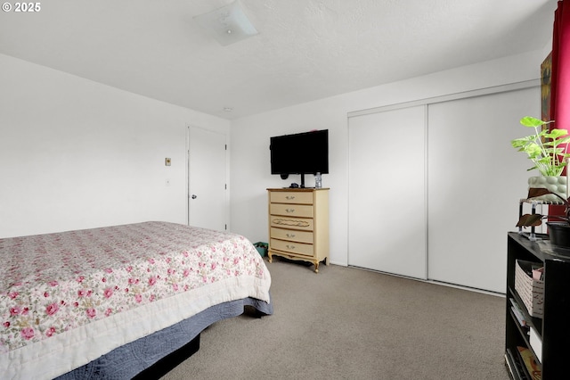 bedroom featuring light carpet, a textured ceiling, and a closet