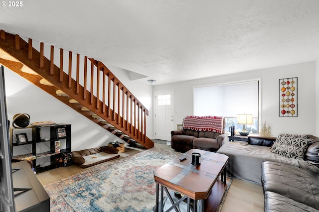 living room featuring wood finished floors, a textured ceiling, and stairs