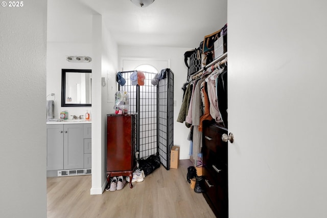 spacious closet featuring light wood-style floors, visible vents, and a sink