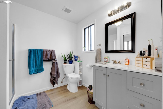 full bath with baseboards, visible vents, toilet, wood finished floors, and vanity