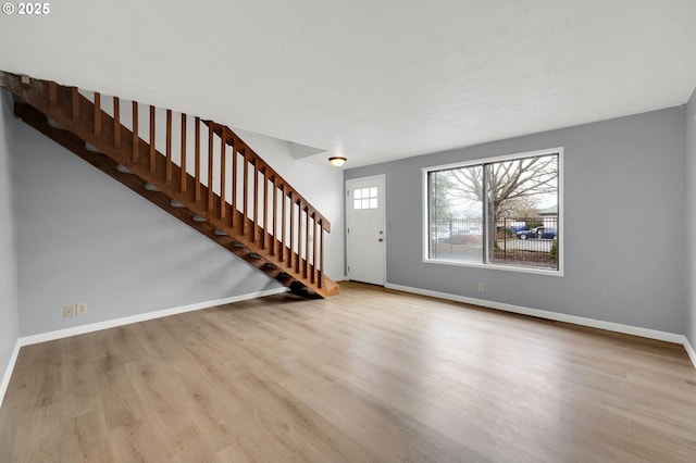 foyer featuring stairway, light wood-style flooring, and baseboards