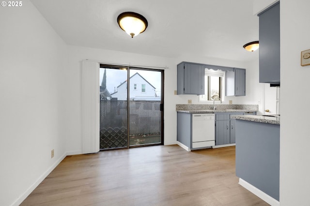 kitchen featuring white dishwasher, light countertops, a wealth of natural light, and gray cabinetry